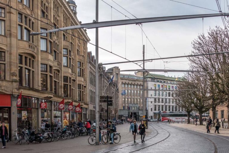 Straße in Den Haag, Fußgänger, Radfahrer, Masten, alte Häuser, Bäume, Straßenbahnschienen