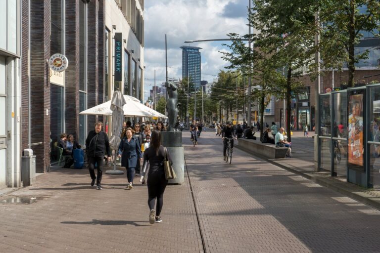 Gehsteig, Radweg und Straßenbahnhaltestelle in Den Haag, "Bagels & Beans", Hochhaus, Radfahrer, Bäume