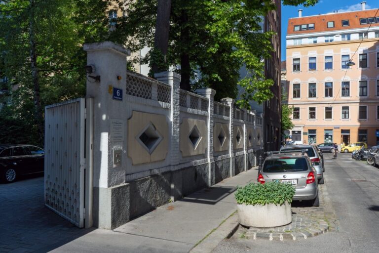 Mauer, Bäume, parkende Autos, Häuser, Straße in Wien-Josefstadt