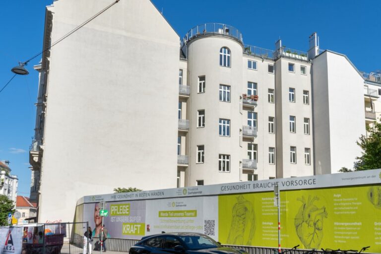 leerer Bauplatz hinter einer Plakatwand in Wien-Josefstadt, daneben Wohnhäuser der Gründerzeit