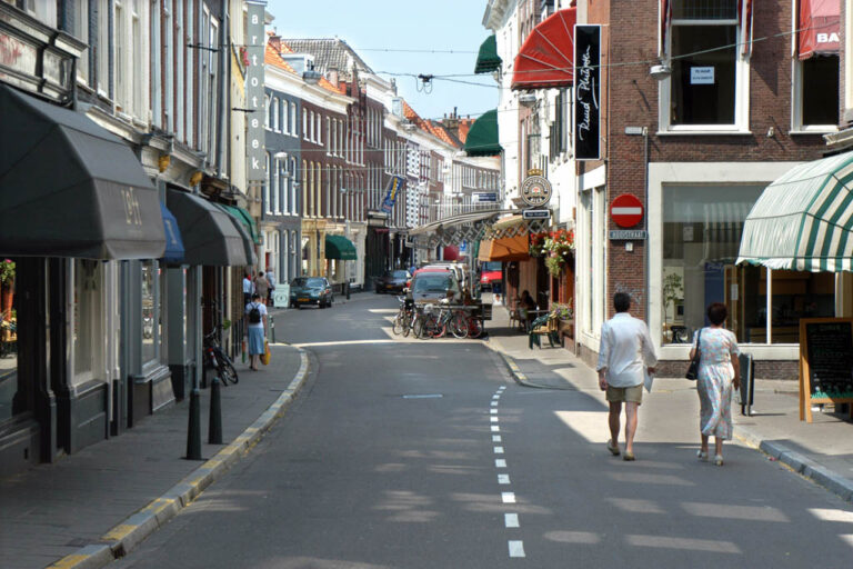 Fußgänger gehen durch eine Straße mit alten Häusern