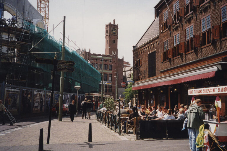 Zentrum von Den Haag, Haus wird gebaut, Leute sitzen vor einem Restaurant, Turm mit Uhr