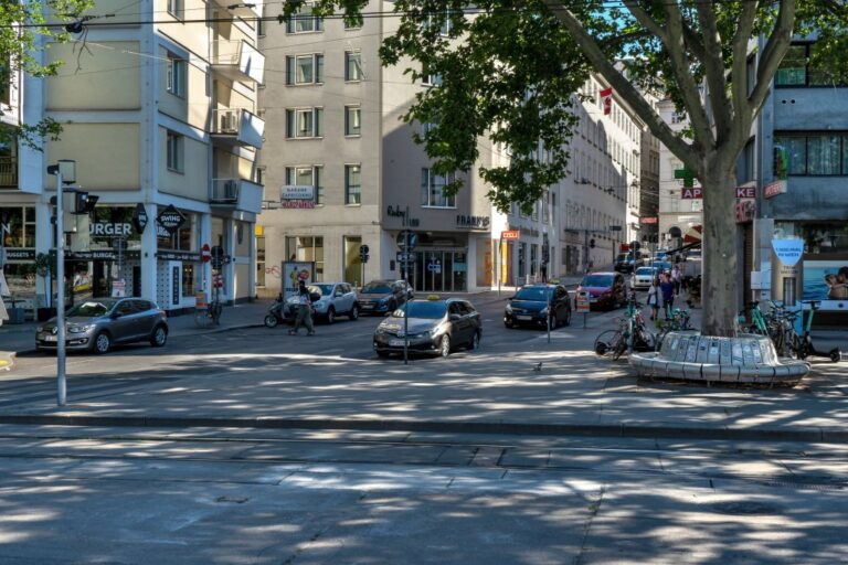 Platz in Wien, Autos, Bahngleise, Baum, Häuser